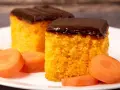 Due fette di ciasto marchewkowe, soffice e arancione, ricoperte di glassa al cioccolato fondente, con fettine di carota fresca intorno.