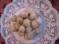 Un mucchietto di castagnole montersino, dolcetti dorati e zuccherati, adagiati su un centrino di pizzo bianco.