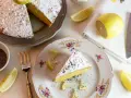Una fetta di babka cytrynowa, cosparsa di zucchero a velo e semi di papavero, con spicchi di limone e una ciotolina di semi.