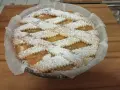 Una deliziosa crostata pasqualina salata, con un intreccio di pasta frolla cosparso di zucchero a velo, pronta per essere gustata.