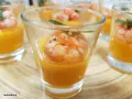 Deliziosi gamberi aperitivo in bicchierini con crema arancione e foglioline verdi.