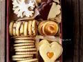Scatola piena di deliziosi ciasteczka maślane: a fiocco di neve, al cioccolato, con ripieno di caramello e a forma di cuore.
