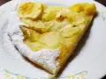 Una fetta di pizza con le mele, cosparsa di zucchero a velo, su un piatto bianco con decorazioni floreali.