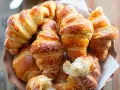 Raffinati rogaliki drożdżowe, dorodnie wyrośnięte i posypane cukrem pudrem, kuszą swoim złotym kolorem.
