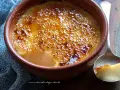 Un delizioso krem kataloński con crosta caramellata dorata, servito in una ciotola di terracotta.