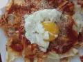 Spianata sarda come farcirla: croccante base con sugo rosso, formaggio grattugiato e un uovo in camicia.