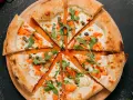 Fette di pizza con salmone affumicato, rucola e capperi, perfette come pizza sticks per un aperitivo.