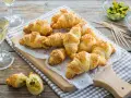 Croissant dorati con ripieno di pasta sfoglia e semi di sesamo, pronti per essere gustati con un bicchiere di vino.