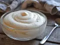Una ciotola di soffice crema al mascarpone senza lattosio, pronta per essere gustata. Un cucchiaino argentato attende accanto.