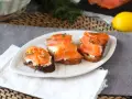 Tre bruschette con salmone affumicato, formaggio cremoso e aneto, guarnite con scorza di limone.