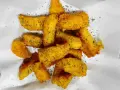 Croccanti bastoncini di polenta taragna fritta, dorati e conditi con erbe aromatiche, adagiati su carta bianca.
