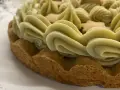 Torta con bordi croccanti e un abbondante strato di ganache pistacchio, decorata con biscotti a forma di stella.