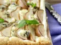 Deliziosa pizza zola e pere su pasta sfoglia croccante, guarnita con foglie di menta fresca. Un connubio di sapori unico.