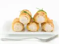 Cannoli salati ripieni di tonno, guarniti con erba cipollina, su un piatto bianco con forchetta.