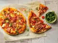 Pizza con mascarpone, pomodorini, prosciutto crudo e rucola, su carta forno.