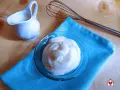 Crema soffice e vellutata, una delizia preparata con yogurt greco. Accanto, una piccola brocca e una frusta, pronti per creare altre bontà.