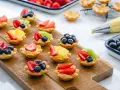 Deliziosi cestini di frutta ricetta, preparati con fragole, mirtilli, kiwi e ananas su una base di crema.