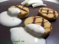 Deliziosi medaglioni di ceci grigliati, serviti con una salsa bianca cremosa e guarniti con erbe aromatiche.