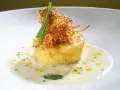 Flan di porri con salsa di acciughe, guarnito con cipolla croccante e erbe aromatiche. Un piatto raffinato che celebra i sapori del mare e della terra.