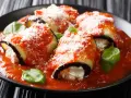 Involtini di melanzane vegetariani ripieni di ricotta, coperti da sugo di pomodoro e parmigiano, guarniti con basilico fresco.