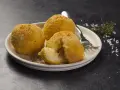 Tre arancini dorati su un piatto, uno aperto rivela il ripieno di riso. Un invito a provare il nostro arancini ricetta.