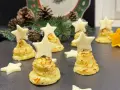 Alberelli di patate decorati con stelle di formaggio, su un piatto natalizio con pigne e rami di abete.