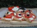 Fette di pizza saporita con pomodoro fresco, mozzarella filante e olive nere. Ingredienti semplici per un gusto autentico.