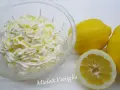 Una ciotola di panna montata con scorza di limone, accanto a limoni freschi. Perfetta per una ganache al limone leggera e profumata.