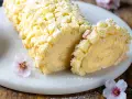 Tronchetto mimosa soffice e cremoso, decorato con briciole di pan di Spagna e fiori rosa.