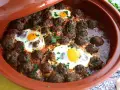 Polpette marocchine in umido con uova cotte nel tajine, guarnite con prezzemolo fresco.