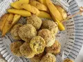 Polpette di verza e ricotta dorate e croccanti, servite con spicchi di patate fritte su carta di giornale.
