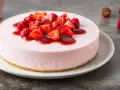 Cheesecake rosa con fragole fresche e salsa, un dolce delizioso, perfetto per ogni occasione.