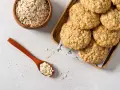Biscotti di avena dorati e croccanti, con fiocchi d'avena in una ciotola e un cucchiaio.