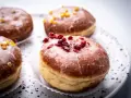 Paczki ricchi e golosi, con glassa lucida e decorazioni di frutta secca. Un invito a provare il paczki przepis perfetto.