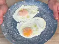 Due frittelle di uova, cotte alla perfezione, servite su un piatto blu decorato. Un classico per iniziare la giornata.
