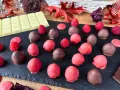 Cioccolatini al lampone, alcuni ricoperti di cioccolato fondente, altri di rosa, con lamponi freschi e tavoletta di cioccolato bianco.