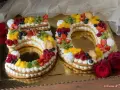 Torta 50 anni con panna, frutta fresca e biscotti a forma di numero. Un dolce colorato e delizioso per festeggiare un traguardo importante.