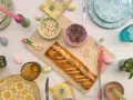 Torta pasqualina senza uova dorata, con mandorle e pinoli, decorata con uova colorate e candela pasquale.