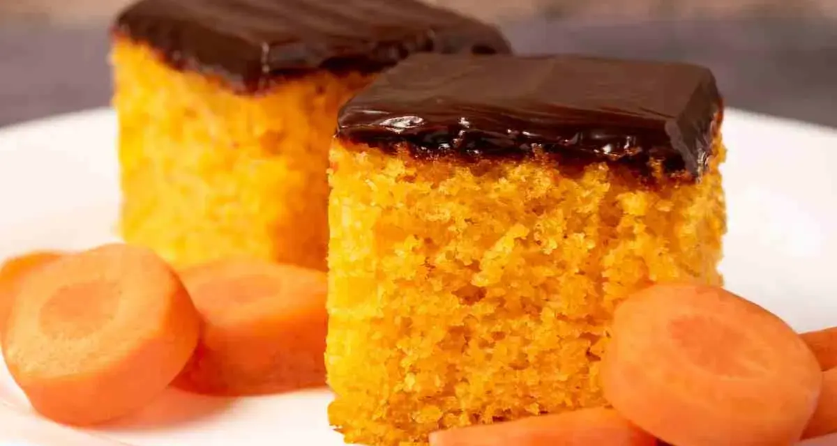 Due fette di ciasto marchewkowe, soffice e arancione, ricoperte di glassa al cioccolato fondente, con fettine di carota fresca intorno.