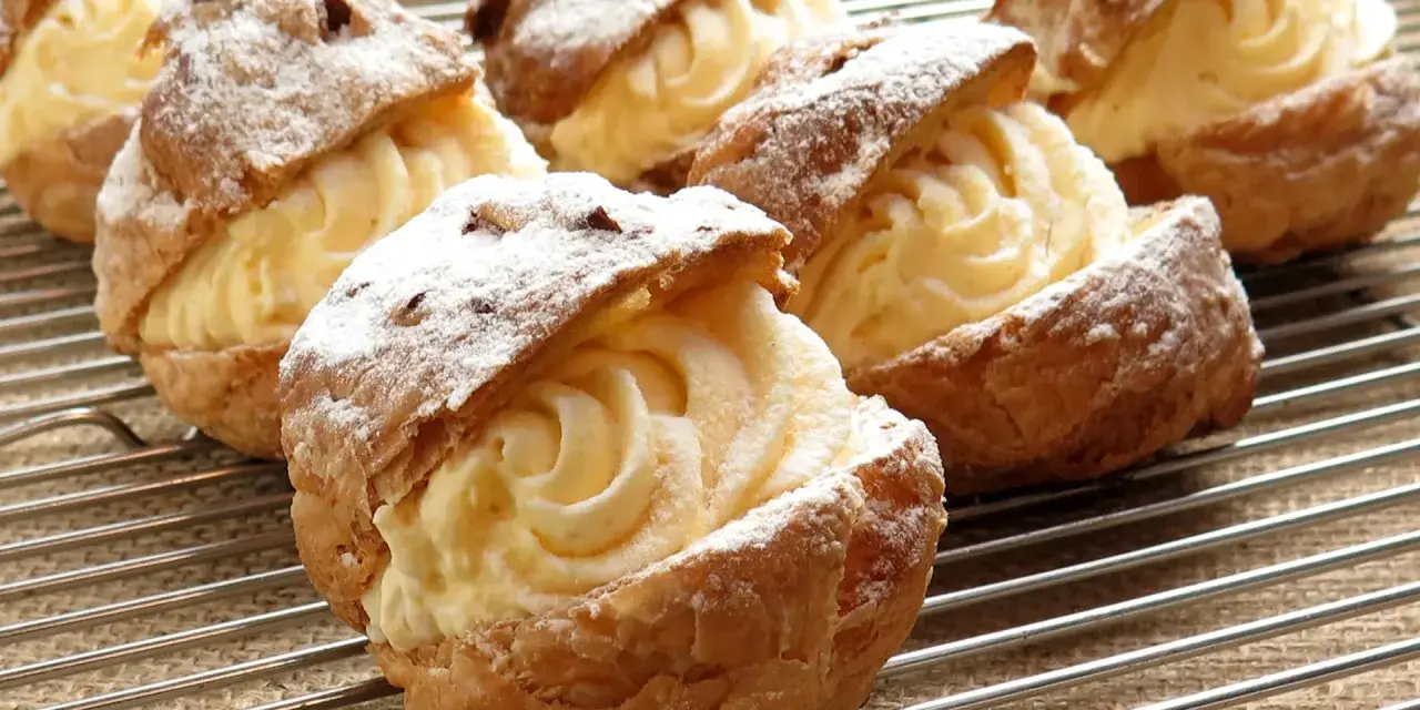 Bignè ripieni di crema pasticcera, spolverati di zucchero a velo. La farina per bignè W è perfetta per questa preparazione.