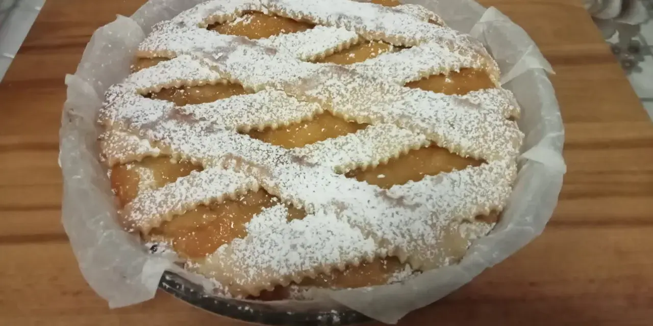 Una deliziosa crostata pasqualina salata, con un intreccio di pasta frolla cosparso di zucchero a velo, pronta per essere gustata.