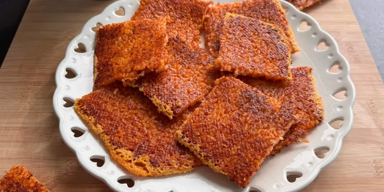 Schiacciata di riso croccante, dorata e invitante, servita su un piatto bianco decorato con cuoricini. Perfetta per uno snack goloso.