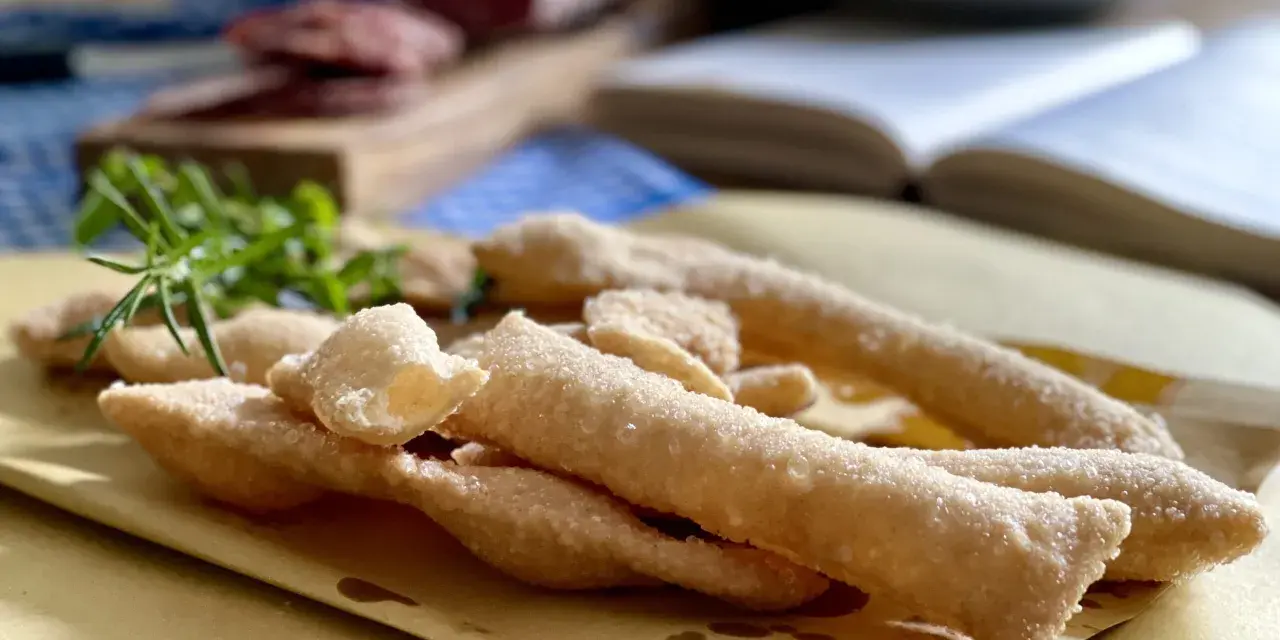 Sgabei fritti dorati e croccanti, profumati con rosmarino fresco, pronti per essere gustati con salumi e formaggio.