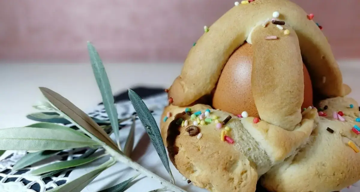 Dolci biscotti con uovo sodo, decorati con zuccherini colorati, pronti per essere gustati. Un ramoscello d'ulivo completa la scena.