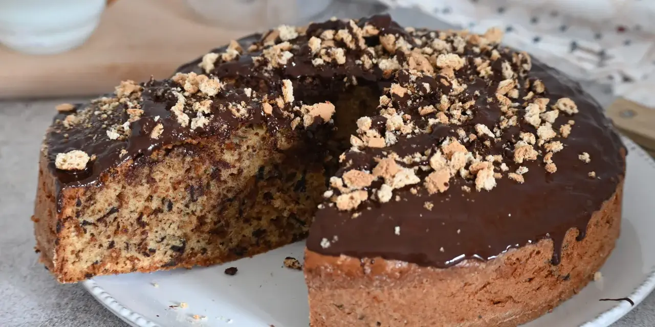 Torta soffice con amaretti e cioccolato fondente, glassata al cioccolato e cosparsa di briciole croccanti.