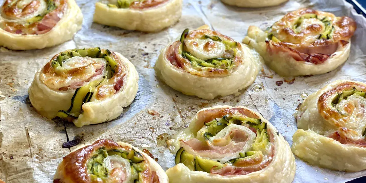 Rotolini dorati di pasta sfoglia con zucchine e scamorza filante, appena sfornati e pronti per essere gustati.