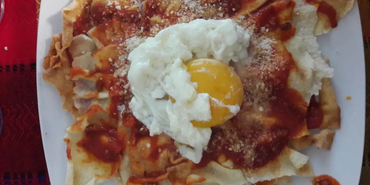 Spianata sarda come farcirla: croccante base con sugo rosso, formaggio grattugiato e un uovo in camicia.