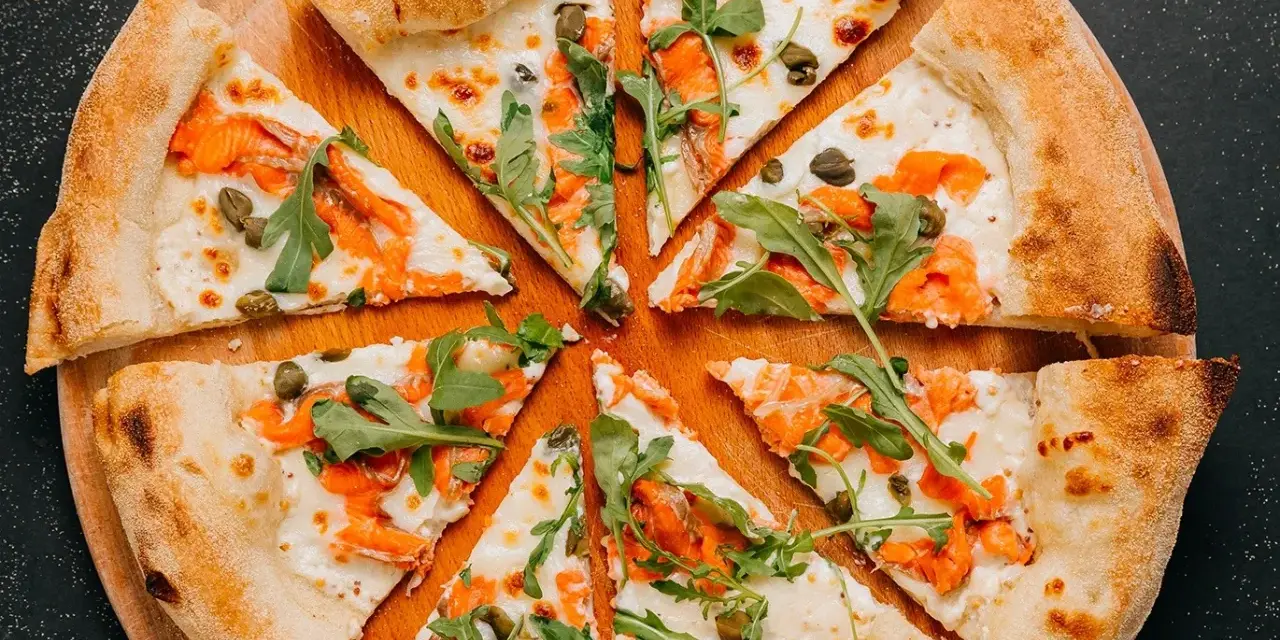 Fette di pizza con salmone affumicato, rucola e capperi, perfette come pizza sticks per un aperitivo.
