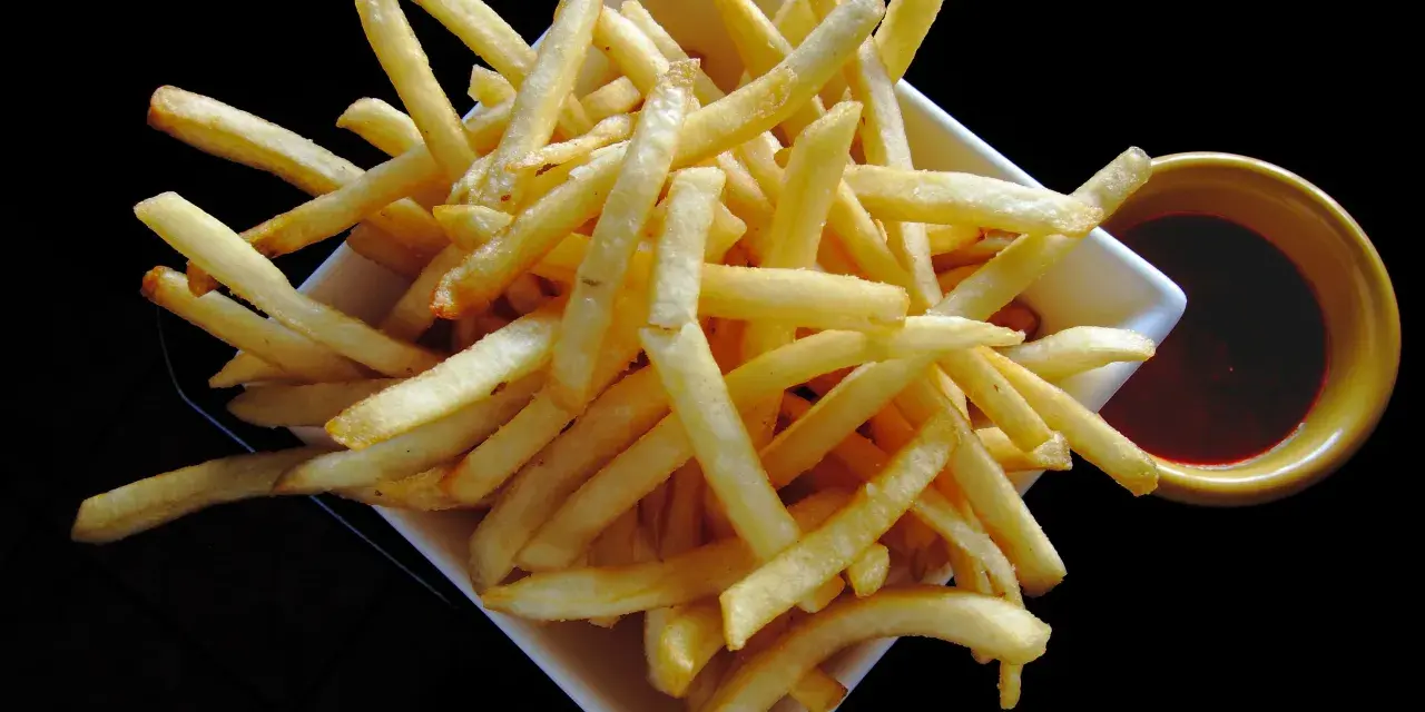 Un piatto di croccanti patatine fritte, perfette per un aperitivo, con una ciotolina di salsa rossa. Un classico intramontabile, come i veri frytki po włosku.