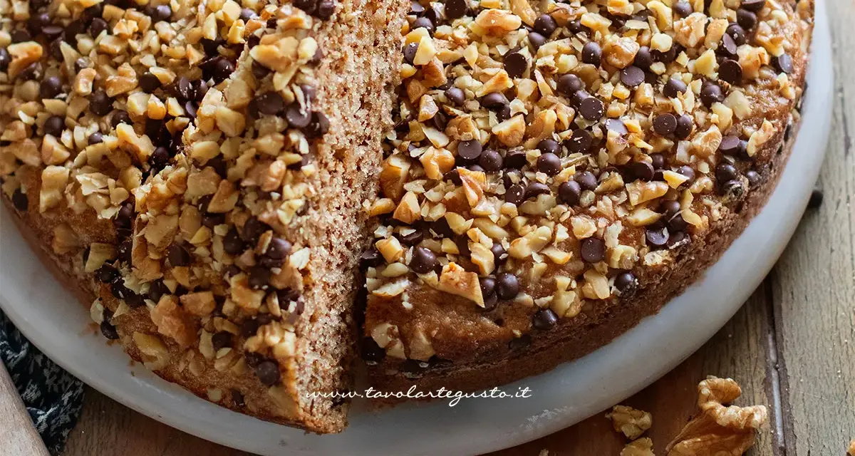 Torta noci e amaretti, soffice e golosa, ricoperta di noci tritate e gocce di cioccolato.